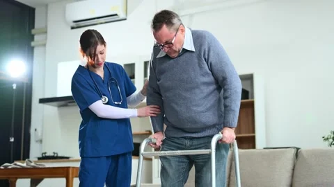 Nurse helps elderly man stand with walker during a home care session. Conce.. Video stock 316458767