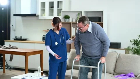 Nurse helps elderly man stand with walker during a home care session. Conce.. Stock Footage 316458769