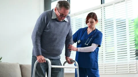 Nurse helps elderly man stand with walker during a home care session. Conce.. Stock Footage 316458785