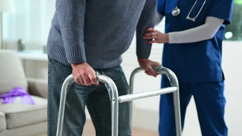Nurse helps elderly man stand with walker during a home care session. Conce.. Stock Footage 316458864