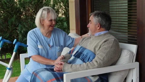 Nurse holding hands of elderly man sitting in wheelchair Stock Footage 300171907