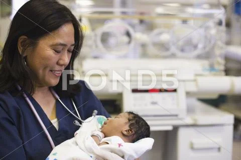 Nurse Holding Newborn Baby In Hospital Nursery