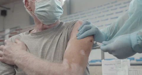 Nurse injecting vaccine or flu shot senior patient who wearing face mask Stock Footage