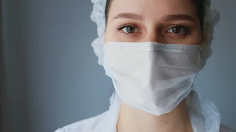 Nurse looking at the camera close-up, the frame is approaching, white background Stock Footage 129308990