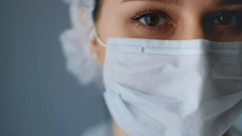 Nurse looking at the camera close-up, the frame starts with a mask and eyes Stock Footage 129309016