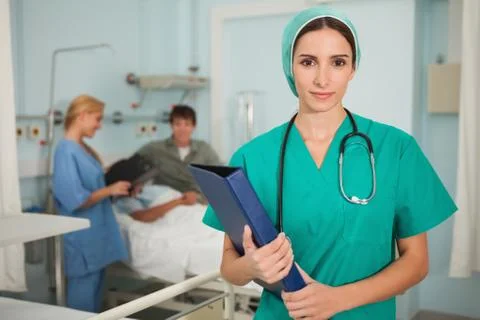 Nurse looking at camera while holding a binder Photos