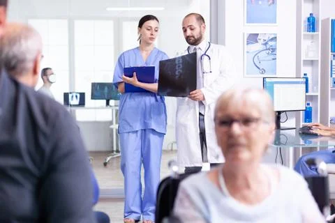 Nurse looking at radiography while talking with doctor 库存照片