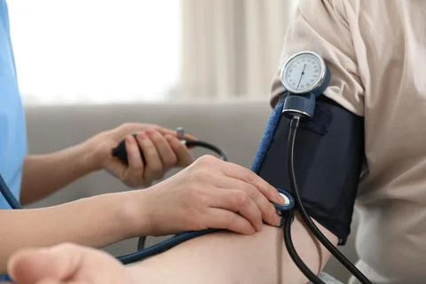 Nurse measuring blood pressure of elderly man indoors, closeup. Assisting sen Stock Photos