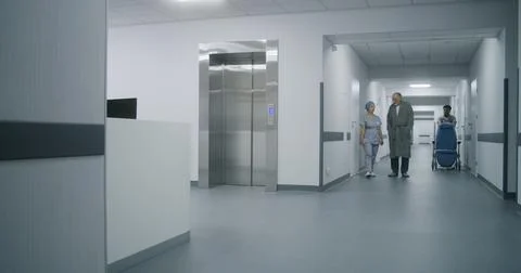 Nurse with old patient wait for elevator in medical center hallway Stock Photos