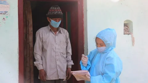 Nurse in ppe kit doing door to door surveys in Indian village regarding Covid-19 Stock Footage 157574222