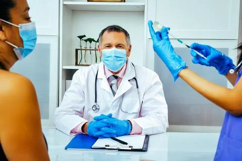 Nurse practitioner making preparing injection to a female patient in hospital Stock Photos