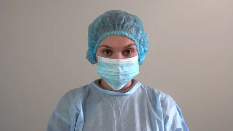A nurse in a protective mask is looking into the camera. in sterile uniform. Stock Footage 127849327
