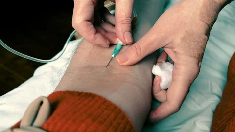 Nurse puts an IV on a man. POV of a man's arm with an IV needle in median vein Stock Footage 257591160