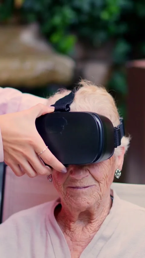 Nurse putting on virtual reality goggles to a senior woman Stock Footage 258210991
