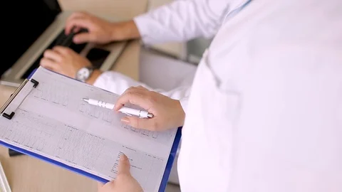 Nurse Reading Data From Paperboard While Doctor Inputing Them On Laptop Stock Footage 87766683