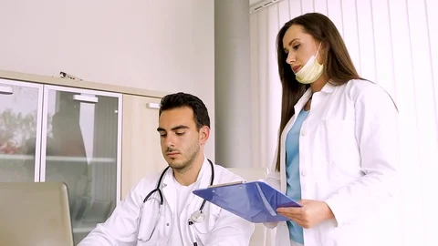Nurse Reading Data From Paperboard While Doctor Inputing Them On Laptop Stock Footage 87766929