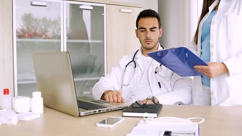 Nurse Reading Data From Paperboard While Doctor Inputing Them On Laptop Stock Footage 87767001