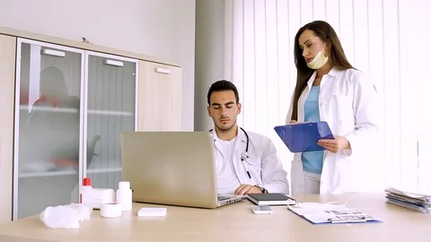 Nurse Reading Data From Paperboard While Doctor Inputing Them On Laptop Video stock 87806977