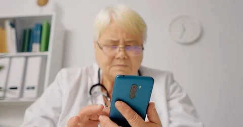 Nurse scrolling on smartphone at workplace. Stock Photos