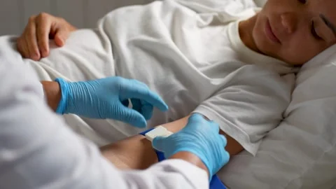 Nurse setting IV drip for patient lying in hospital bed.. Stock Footage 313187405