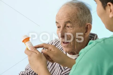 Nurse showing medication to elderly patient Stock Photos