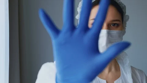 Nurse shows a palm in the camera, looks into the frame, the focus goes from eye Stock Footage 129309002