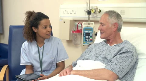 Nurse Sitting By Male Patient's Bed Using Digital Tablet Stock Footage