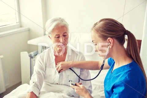 Nurse with stethoscope and senior woman at clinic Stock Photos