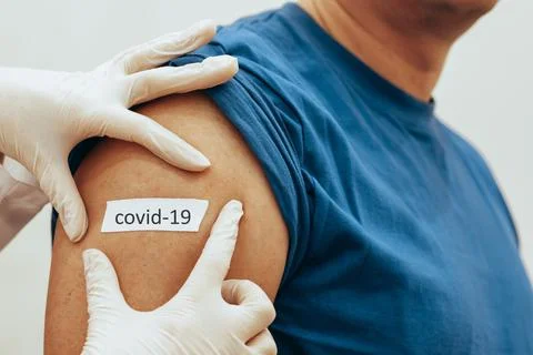 Nurse sticks patch on man after vaccination. The concept of worldwide Stock Photos