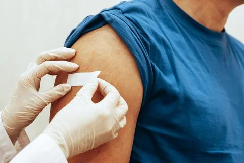 Nurse sticks patch on man after vaccination. The concept of worldwide Stock Photos