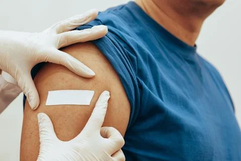 Nurse sticks patch on man after vaccination. The concept of worldwide Stock Photos