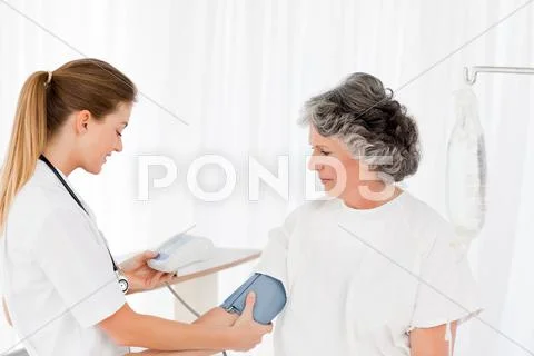 Nurse taking the blood pressure of her patient Stock Photos