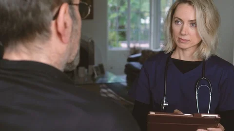 Nurse taking notes on digital tablet while listening to senior patient Vidéo 111237025
