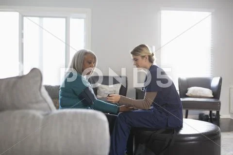 Nurse Taking Patient Blood Pressure In Living Room