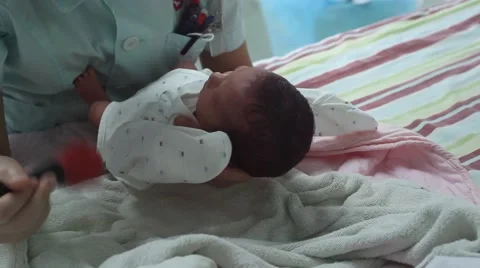 Nurse testing the hearing of an one day old newborn baby after taking a bath Stock Footage 55351769