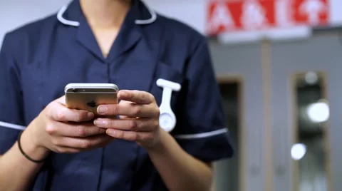 Nurse using cellular mobile phone in hospital with nurse in background Vídeos de archivo 59087327