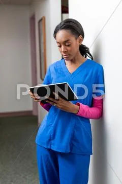 Nurse Using Digital Tablet In Hospital Corridor