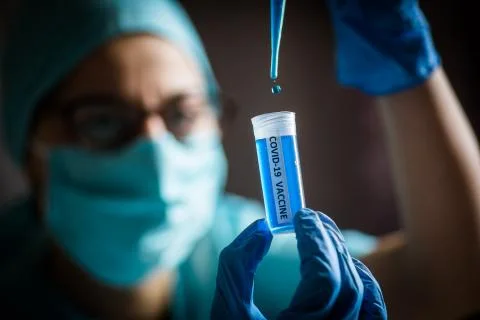 Nurse using a pipette and a recipient with the coronavirus COVID-19 vaccine Stock Photos