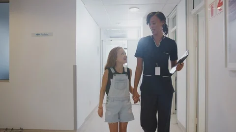 Nurse Walking Holding Hands With Girl Patient In Busy Hospital Corridor Stock Footage
