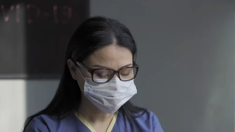 The nurse works at the computer in disposable gloves and a sanitizer that stands Stock Footage 130131367