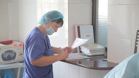A nurse writes a journal entry during an operation. writes in a magazine. notes. Stock Footage 99197785