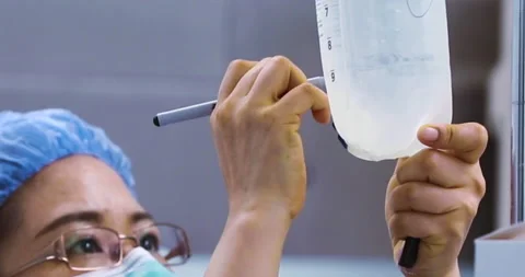 Nurse writing on IV Drip in operating room Stock Footage 146167396