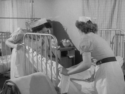 Nurses changing sheets on bed in hospital, 1953, UK Video stock 130677719