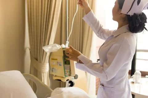 Nurse's hand operating IV machine in patient room Stock Photos