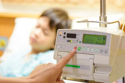 Nurse's hand pressing on infusion pump intravenous IV drip on kid admitted ba Stock Photos