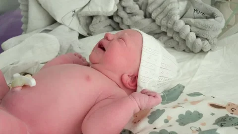 Nurse's hands in blue gloves changing the diaper of a crying newborn baby with Stock Footage 344772072