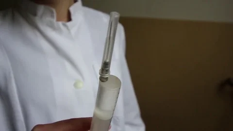 Nurse's hands getting air bubbles out of a syringe before  injection Stock Footage 84855192