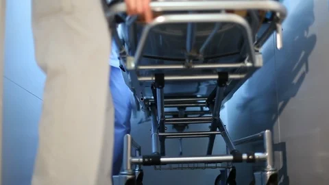 The nurses roll the gurney out of the elevator at the clinic Stock Footage 115989640