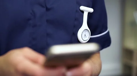Nurses watch fob as nurse uses mobile cell phone Stock Footage 59087329