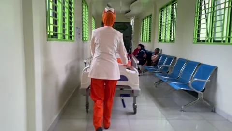 Nurses wearing orange uniforms pushing a hospital bed Stockbeeldmateriaal 333833603